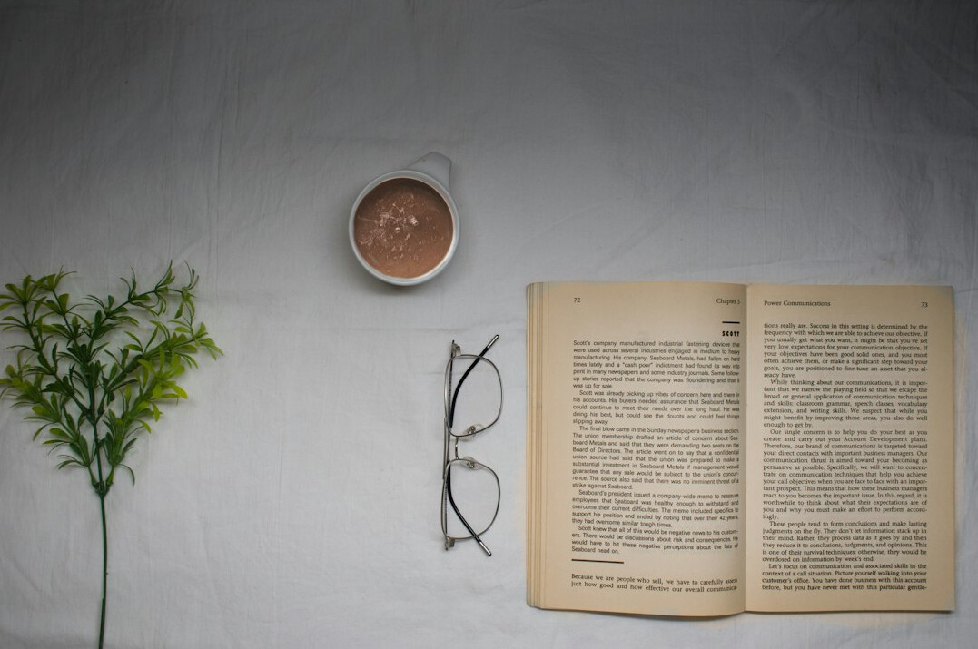 Flat lay of an open notebook, glasses and a warm drink
